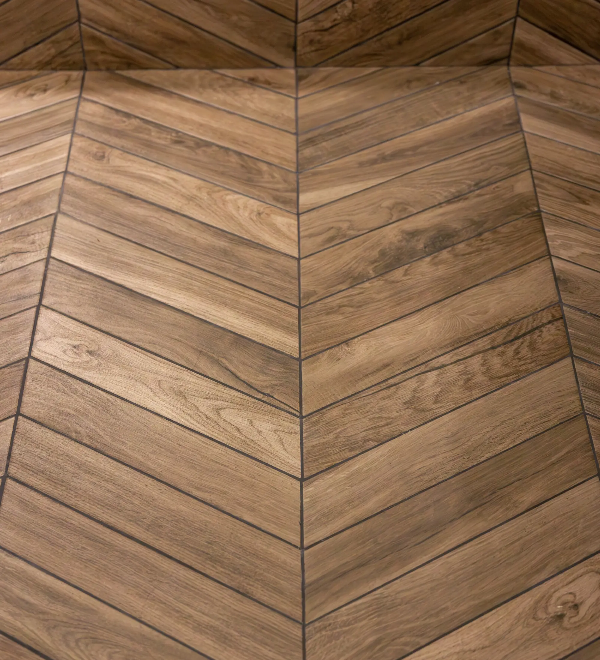 Close-up of a wooden floor arranged in a chevron pattern with natural wood grain and warm brown tones.