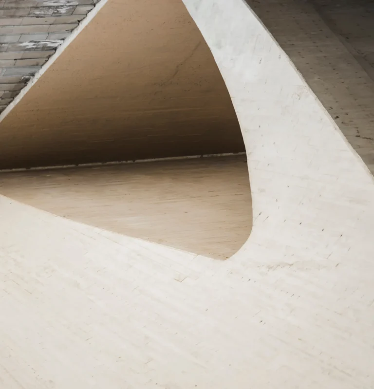 Close-up of a modern concrete architectural structure with smooth curved surfaces and geometric lines forming an abstract opening.